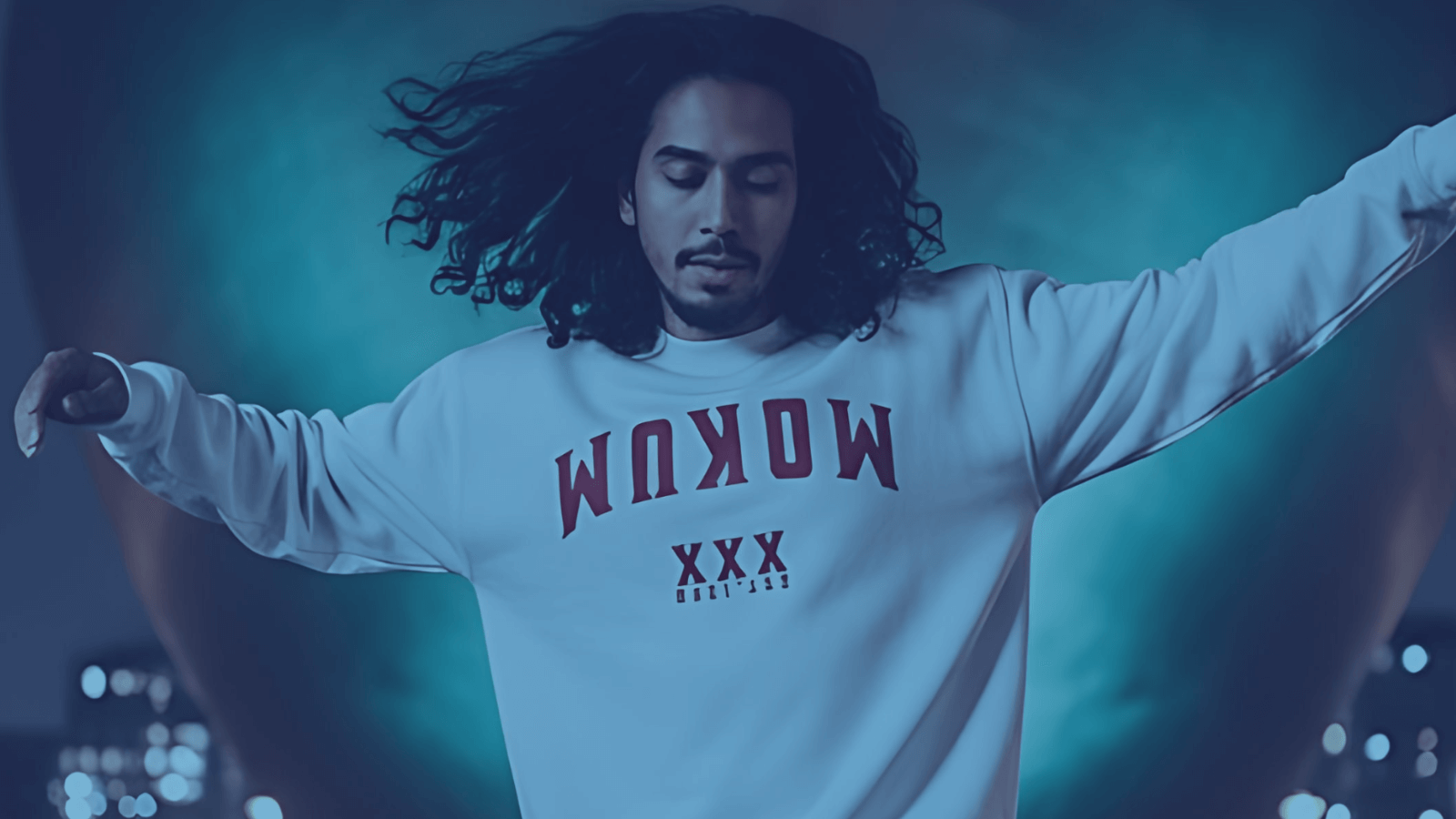 A model wearing a B!NKY COMFYWEAR sweatshirt outdoors with a vibrant blue background, showcasing stylish urban fashion.
