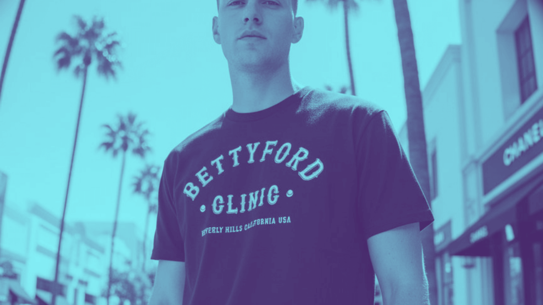 Model wearing a BETTY FORD CLINIC t-shirt in a palm-lined street, showcasing HIGH FASHION. LOW POINTS. LEGENDARY! style.