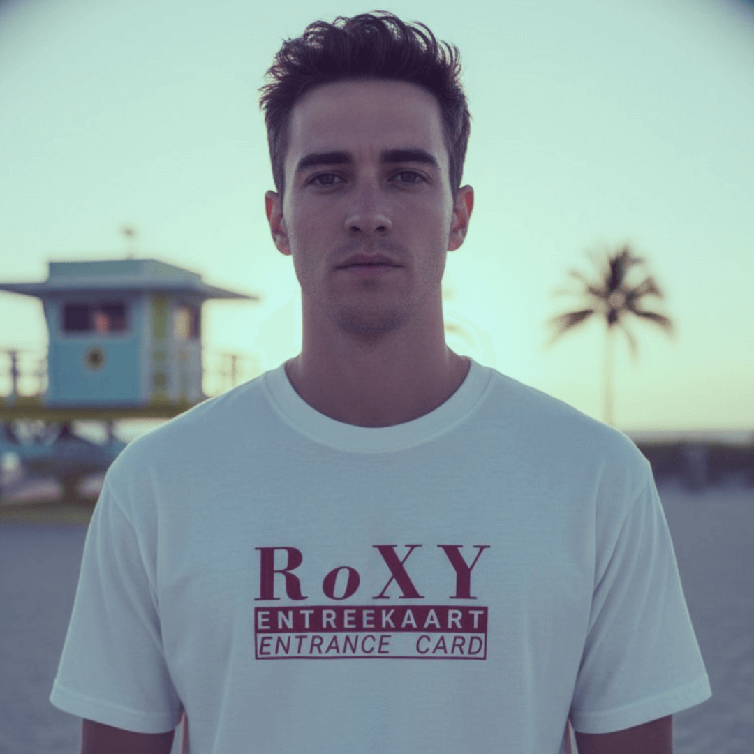 Young man in a white t-shirt with 'RoXY Entrance Card' graphic, standing at a beach location.
