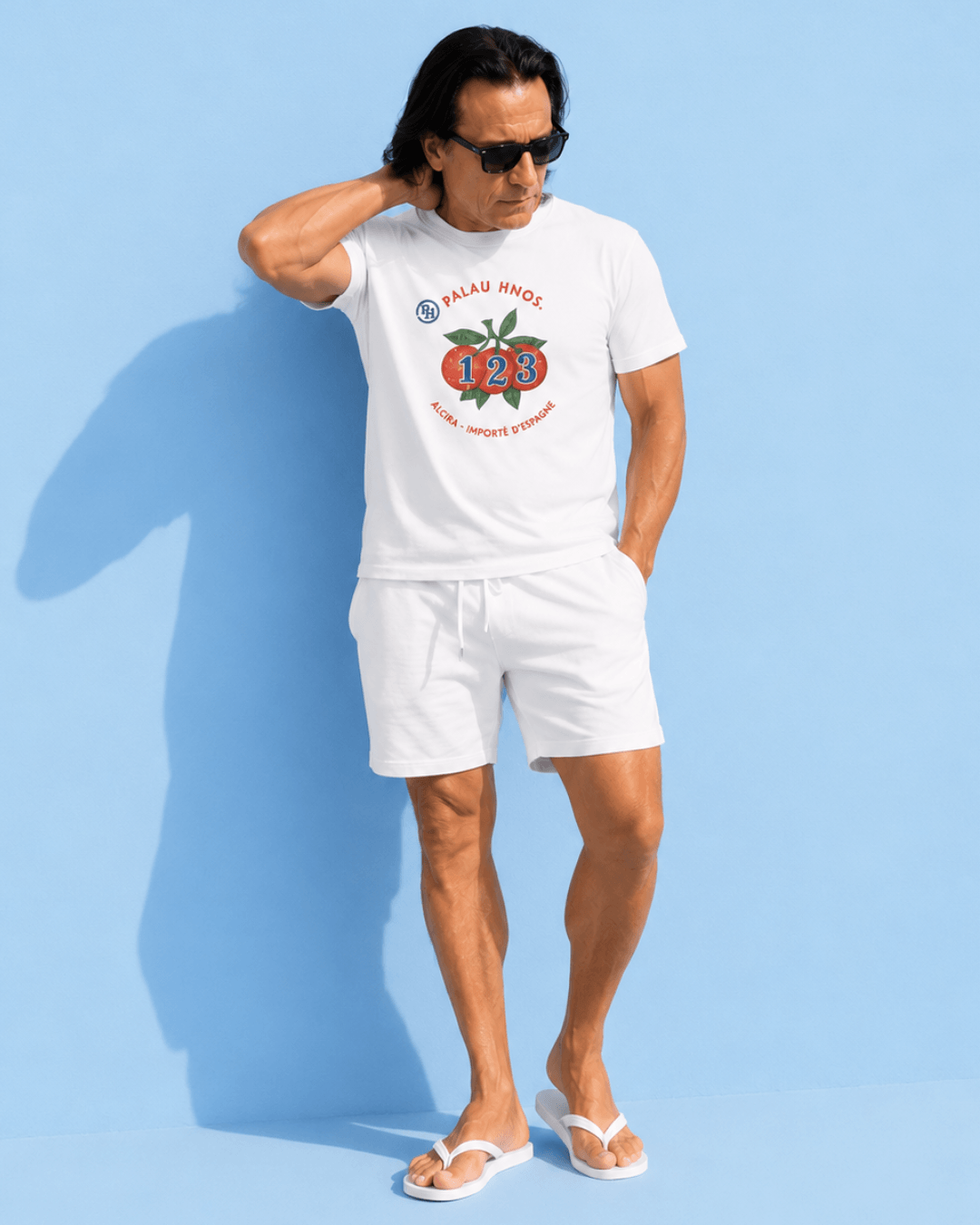 Man in white Alcira Oranges T-Shirt | The Real South-side Deal and white shorts against blue background.