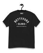 BETTY FORD CLINIC VARSITY T-SHIRT in black, featuring bold vintage lettering, hanging on a display.