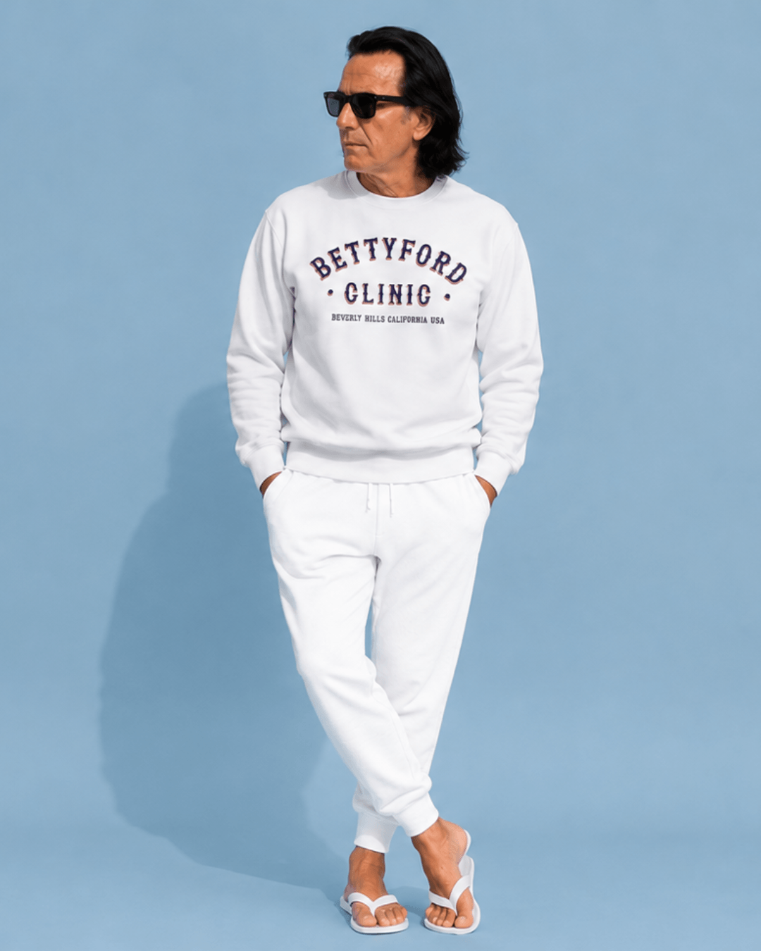 Betty Ford Clinic Sweater | Rehab Club Retro model wearing white sweater and pants against blue background.