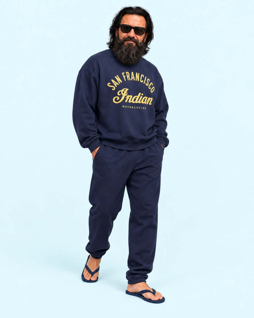 Walter wearing the Navy Bay Area Motorcycle Heavy Sweater with matching joggers and flip-flops against the light blue BINKY studio background.