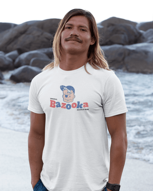 BAZOOKA JOE T-SHIRT worn by a model at the beach, showcasing vintage bubble gum nostalgia and classic 80's charm.