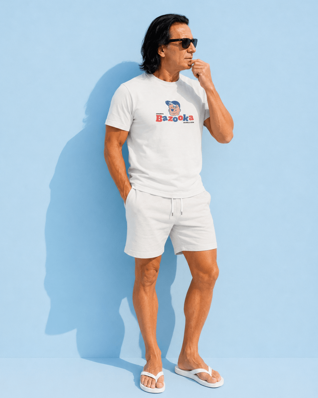 Man wearing Bazooka Joe T-Shirt | Retro Bubblegum Legend with sunglasses and shorts against a blue background.