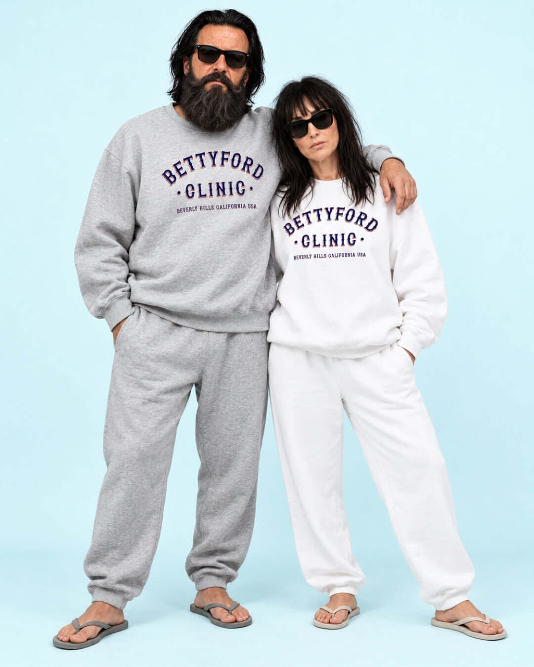 Walter and Helga wearing the BINKY Betty Ford Clinic RWB Heavy Sweater with red, white and navy varsity graphic.