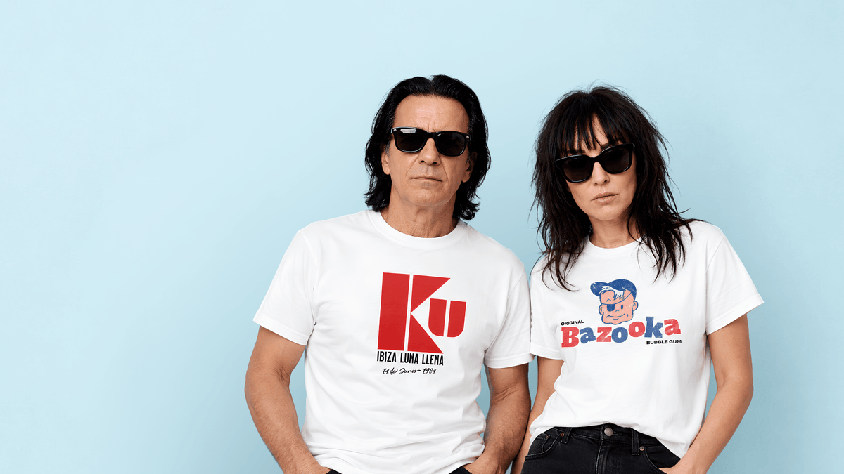 A man and woman wearing trendy t-shirts with designs in front of a blue background, showcasing casual summer fashion.