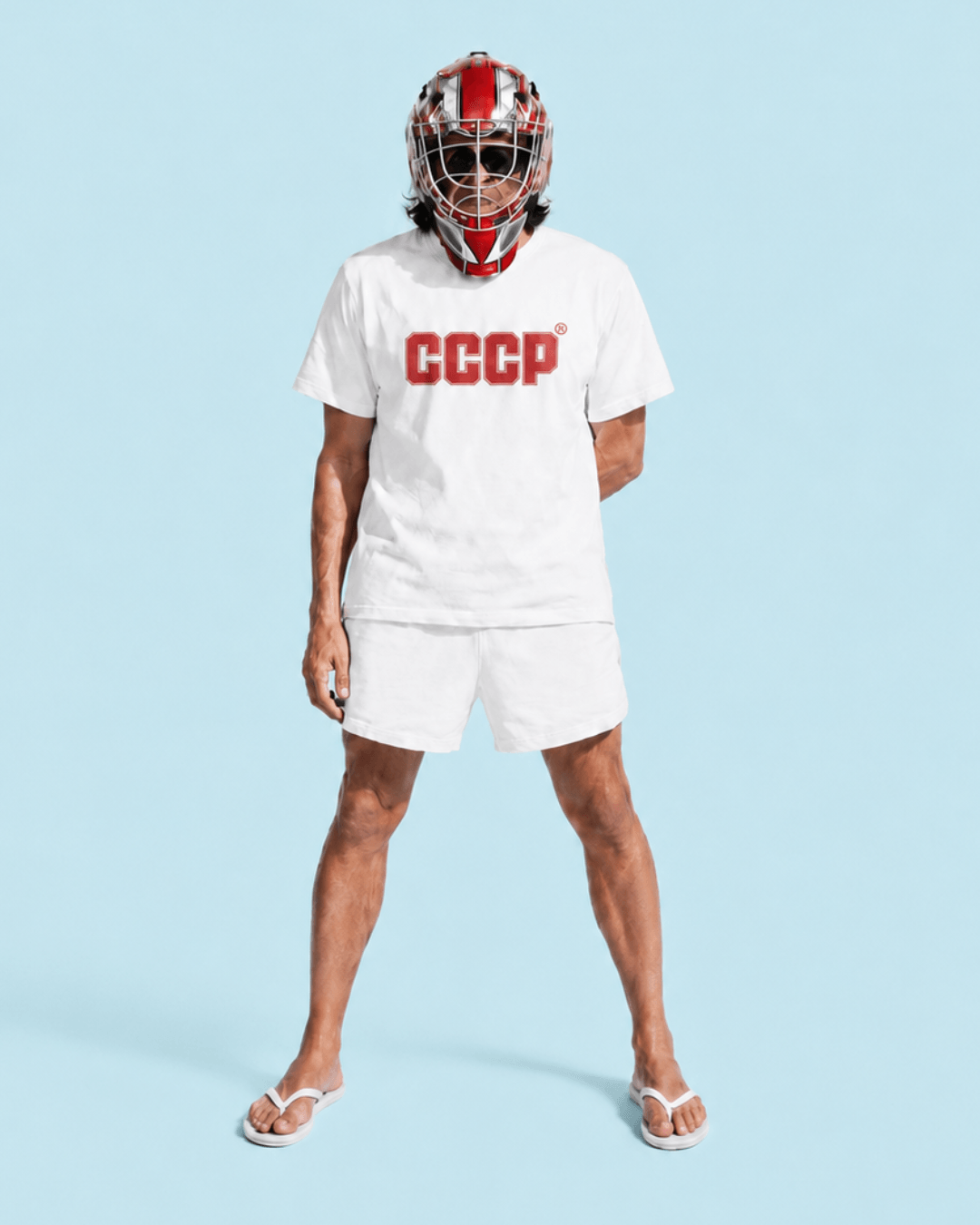 A model wearing a white t-shirt and matching shorts set, featuring a red 'CCCP' logo on the chest, paired with a red and white hockey goalie mask and white flip-flops, set against a solid light blue background.