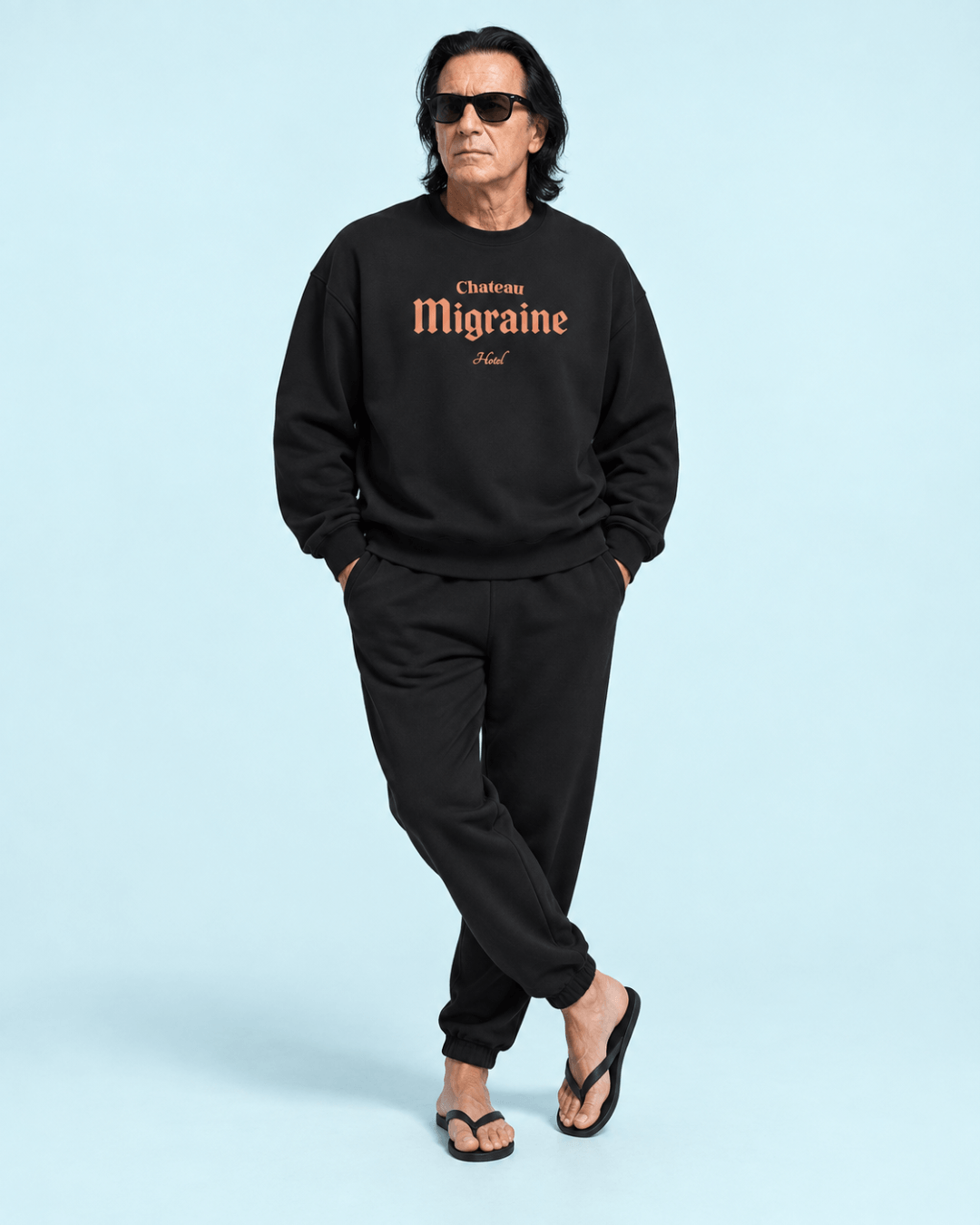 Model wearing Hotel Migraine Heavy Sweater and black sweatpants, showcasing casual French hotel style.