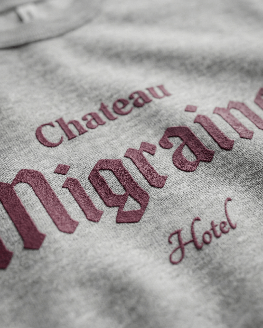 Close-up of the graphic on the HOTEL MIGRAINE HEAVY SWEATER featuring Chateau Migraine Hotel.