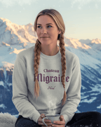 Smiling woman wearing HOTEL MIGRAINE HEAVY SWEATER in snowy outdoor setting, showcasing retro ski and streetwear style.