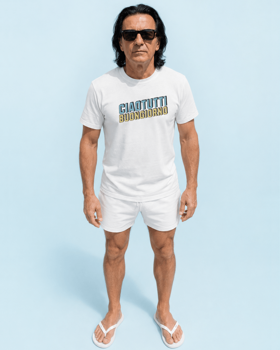 Ciao Tutti T-Shirt | Buongiorno Classic worn by a man in white shorts and sunglasses on a blue background.