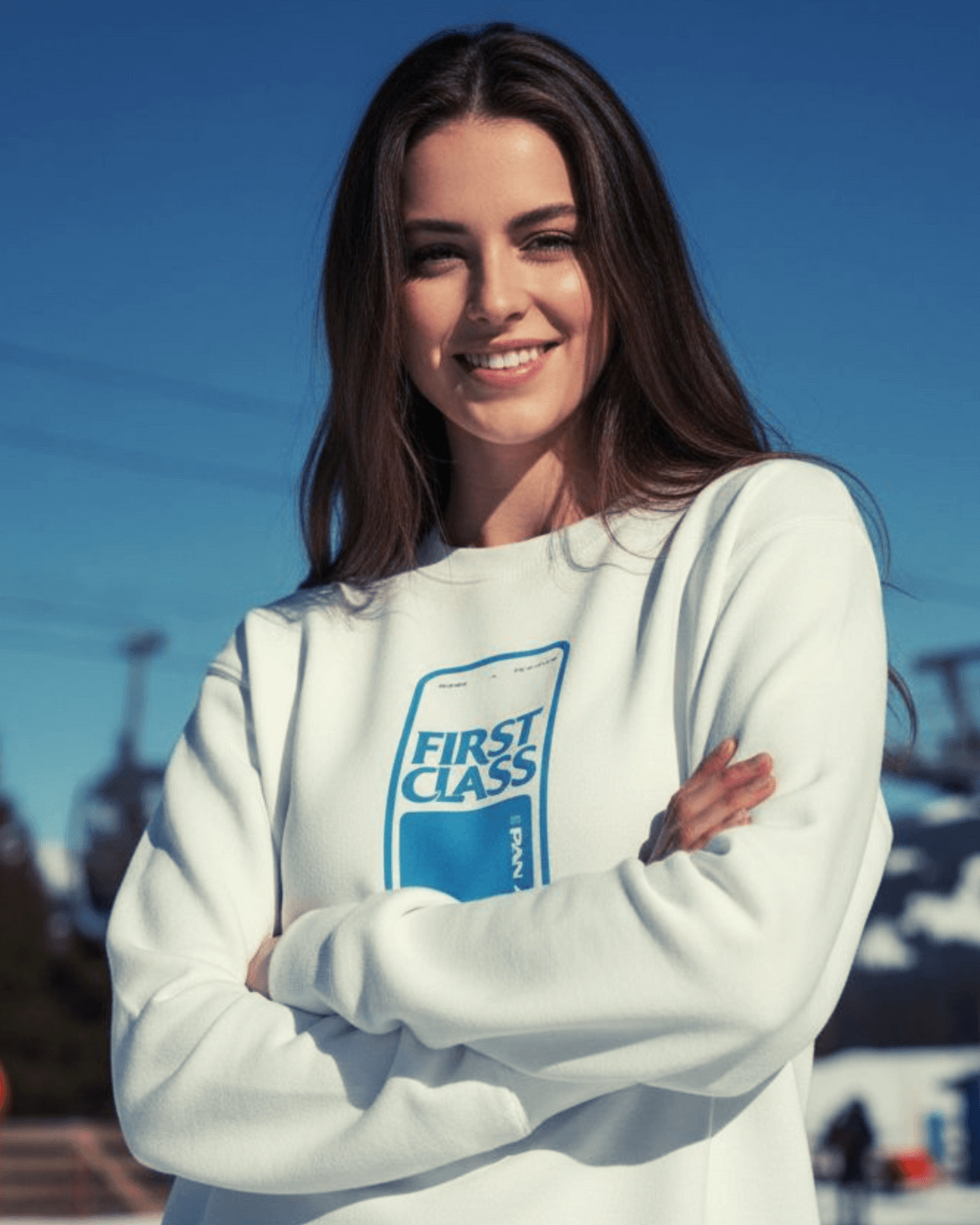 Woman wearing a FIRST CLASS HEAVY SWEATER, showcasing its oversized fit and vintage ski style in a snowy landscape.