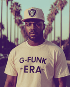 Man wearing a G FUNK ERA T-SHIRT with street backdrop and palm trees, showcasing West Coast hip hop style.