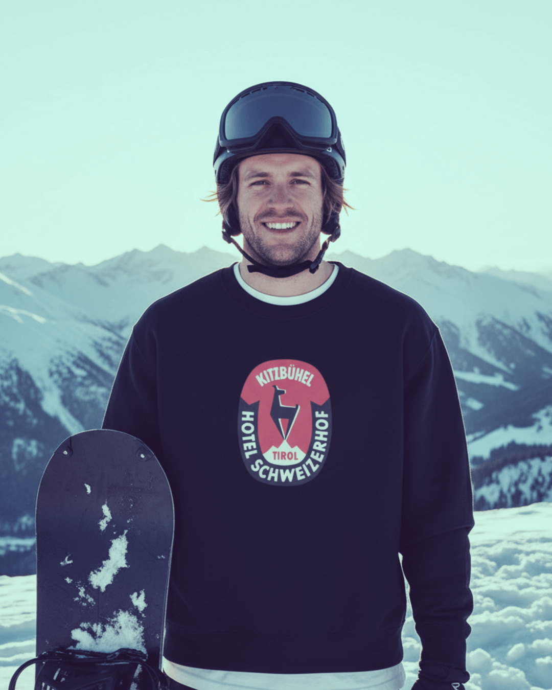 Man wearing HOTEL KITZBÜHEL HEAVY SWEATER with vintage hotel crest, snowy mountains in background, ski culture aesthetic.