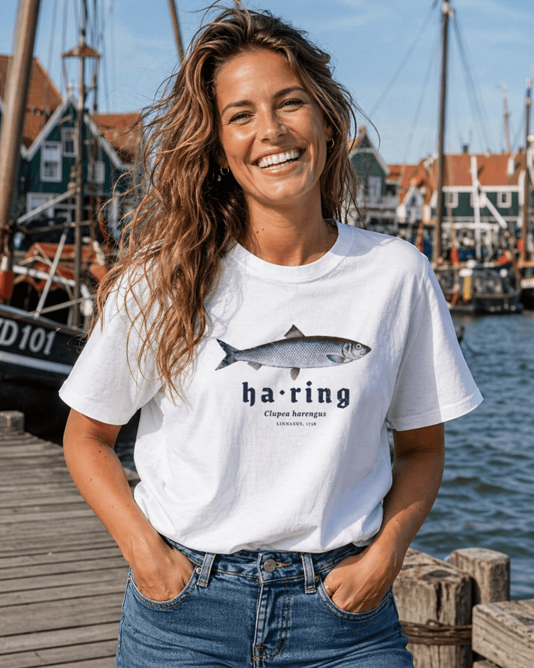 HERRING T-SHIRT | DUTCH CLASSIC RAW featuring a smiling woman in a harbor wearing a stylish Haring T-shirt by Binky Comfywear.