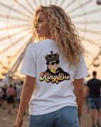 King Dre T-Shirt | Koning van het Levenslied met een vrouwelijke model die het shirt draagt, strand, zonnige achtergrond.