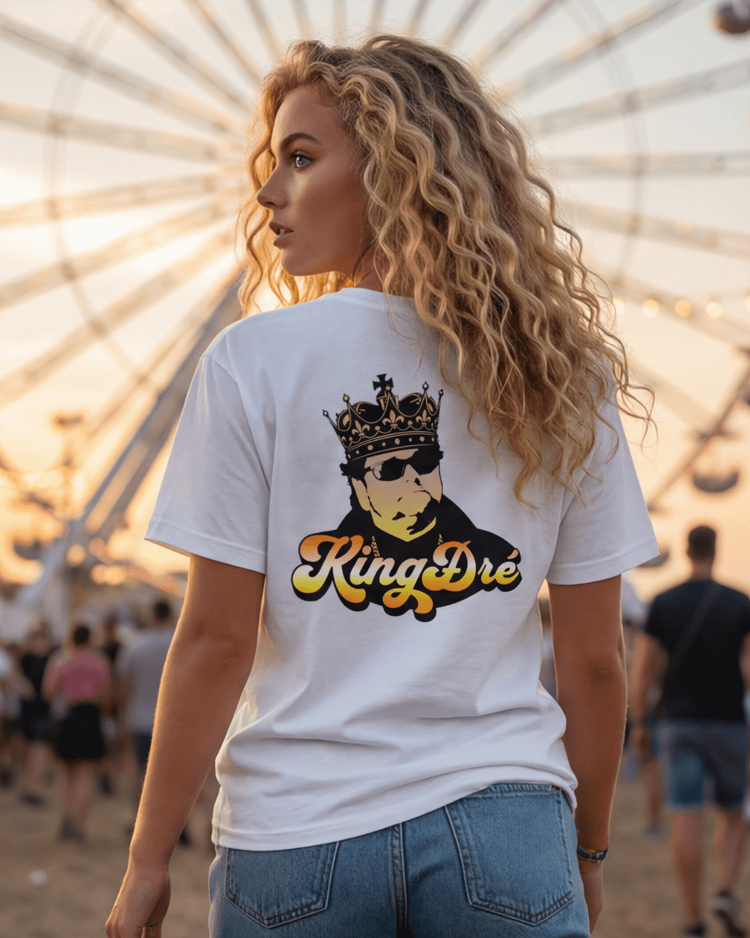 King Dre T-Shirt | Koning van het Levenslied met een vrouwelijke model die het shirt draagt, strand, zonnige achtergrond.