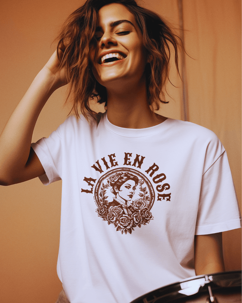 Woman smiling while wearing the La Vie En Rose T-shirt, showcasing a vintage design with floral elements.