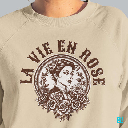 LA VIE EN ROSE sweater with vintage-inspired graphic on a beige background, featuring a woman surrounded by roses.