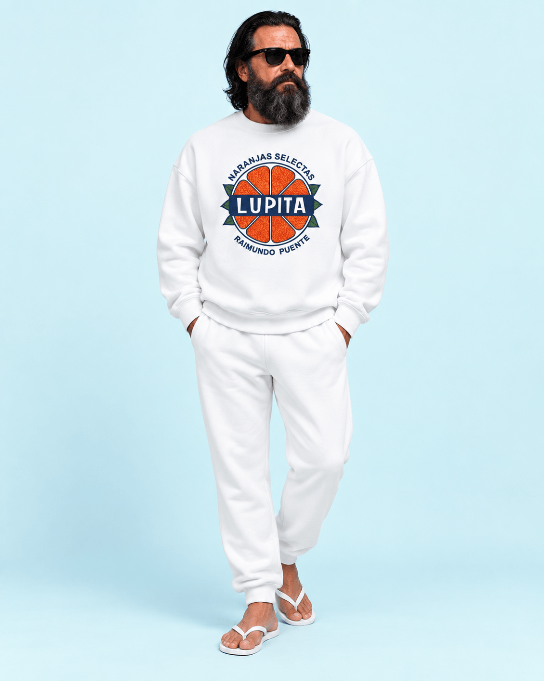 Man wearing Lupita Naranjas Heavy Sweater, sunglasses, and white pants on a light blue background.