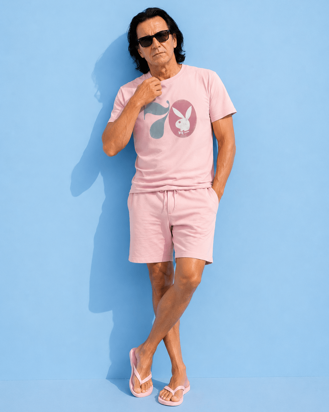 Midnight Hustle '70 T-shirt | The Grotto Bootleg worn by a man in pink clothing against a blue background.
