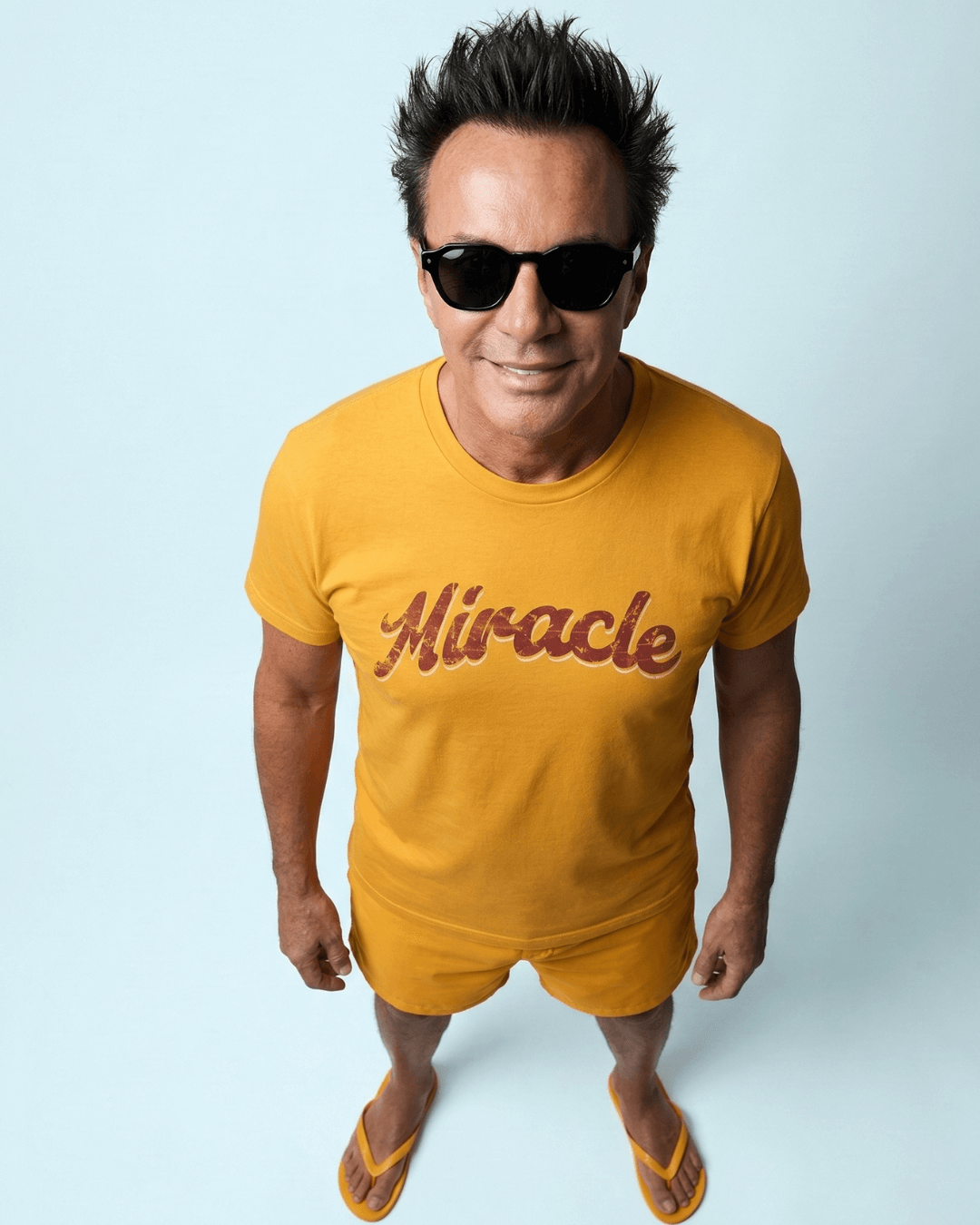 Man wearing MIRACLE T-SHIRT | LUCK IS EARNED in bright yellow, exuding positivity and fun.