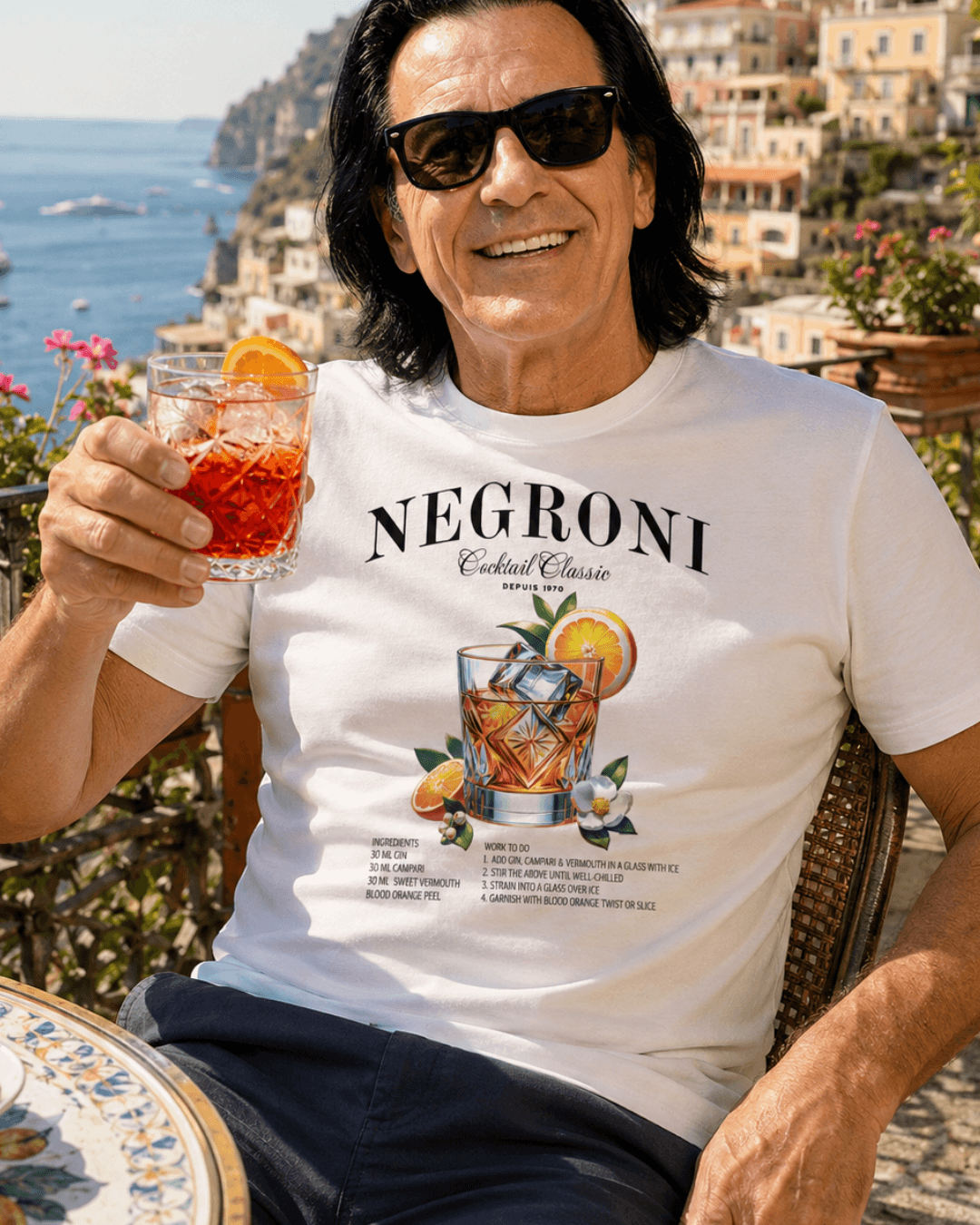 Man wearing NEGRONI T-SHIRT | EXQUISITE LUXURY EDITION, enjoying a cocktail with a scenic background.