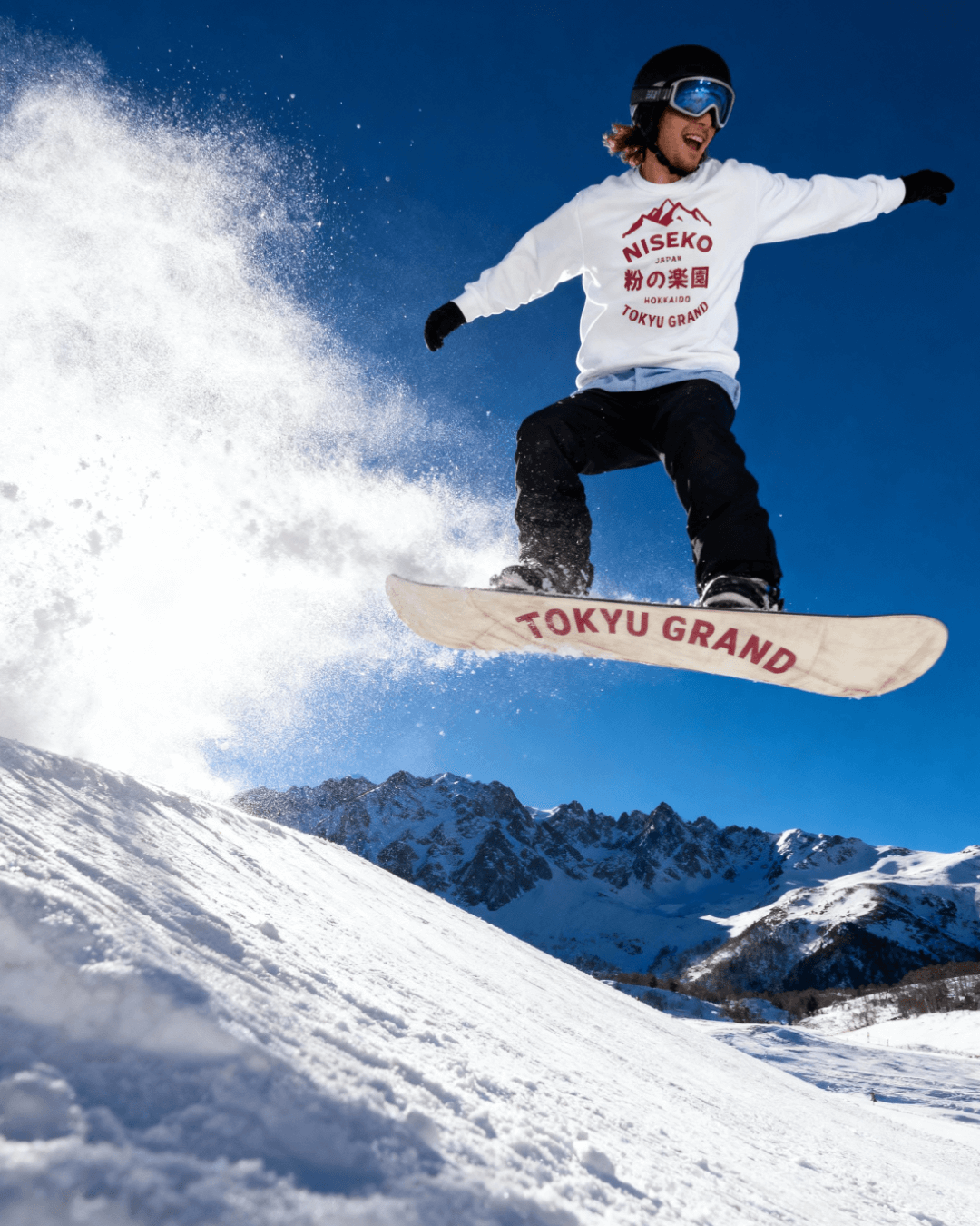NISEKO POWDER PARADISE HEAVY SWEATER being worn by a snowboarder jumping on a snowy mountain.