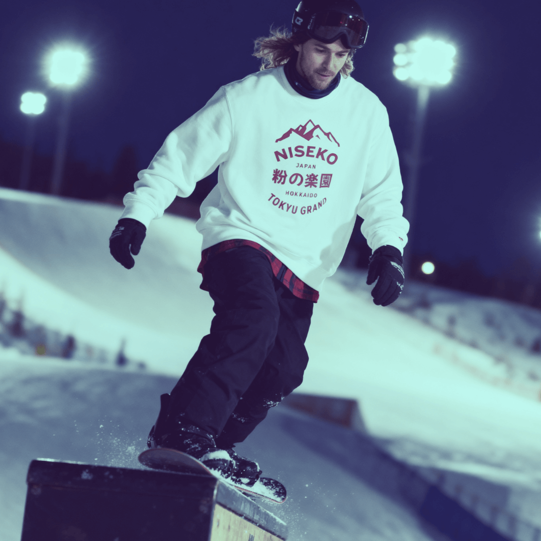 Snowboarder performing a trick on a rail at night in Niseko, Japan, showcasing winter sports and excitement.