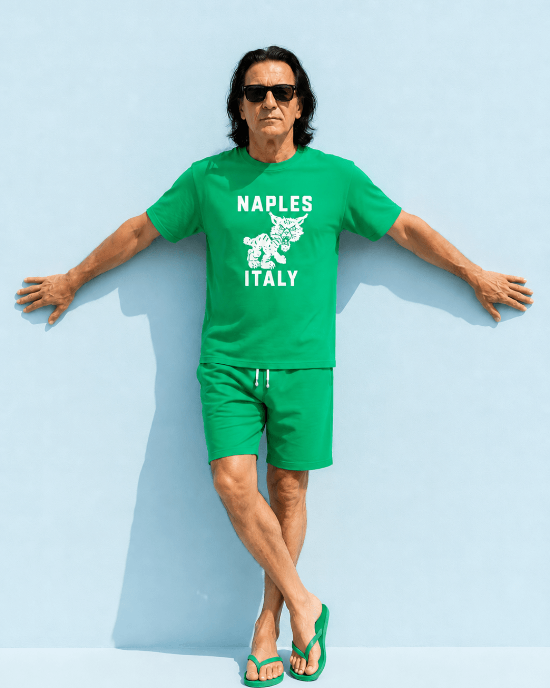 Man wearing Naples Wildcat T-Shirt | Overseas Varsity Bootleg, standing against a light blue background.