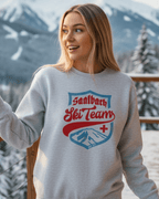 Model wearing SAALBACH SKI TEAM HEAVY SWEATER in a snowy mountain setting, showcasing vintage ski-team graphic.