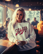 Woman wearing SCHLITZ HEAVY SWEATER in a cozy bar setting, holding a cup.
