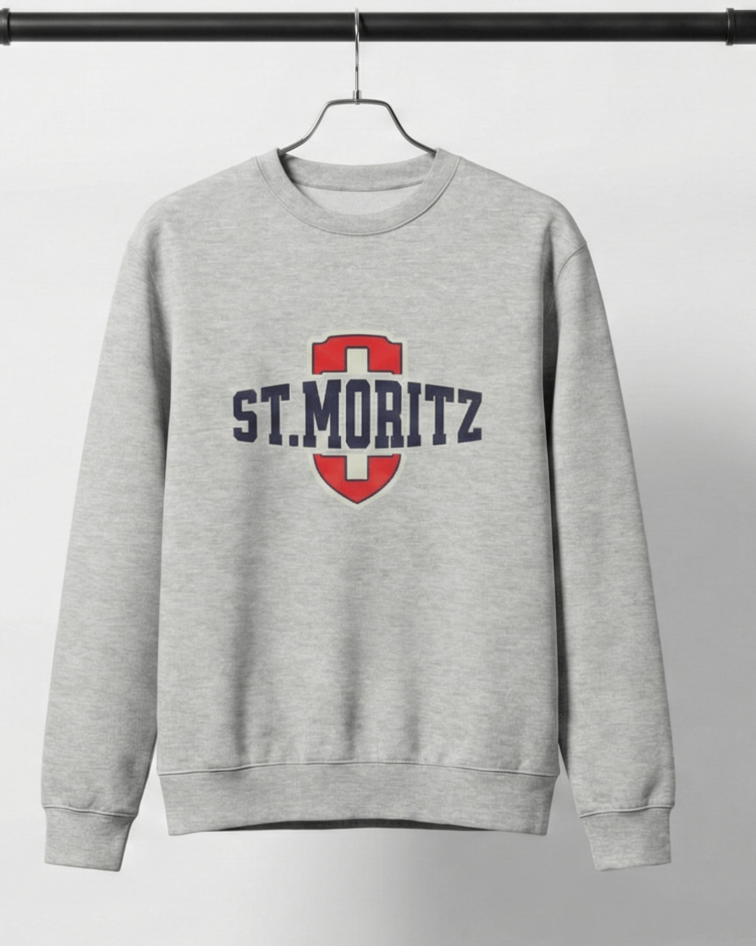 ST. MORITZ HEAVY SWEATER displayed on a hanger, featuring a bold shield design and collegiate-style lettering.