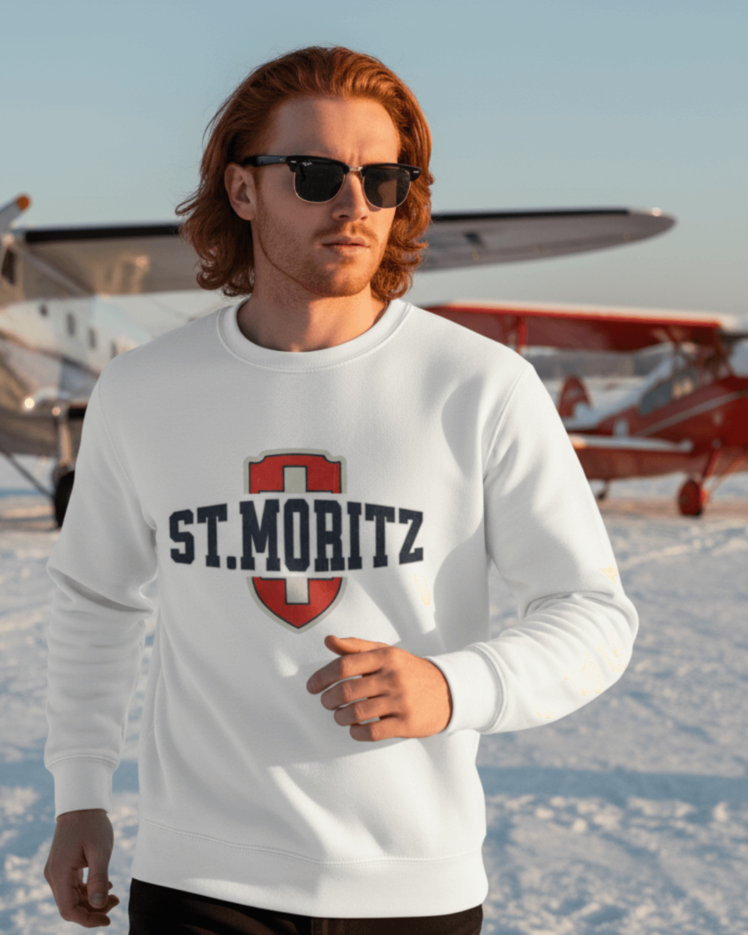 Model wearing ST. MORITZ HEAVY SWEATER outdoors, showcasing Swiss style shield and relaxed fit against a winter backdrop.