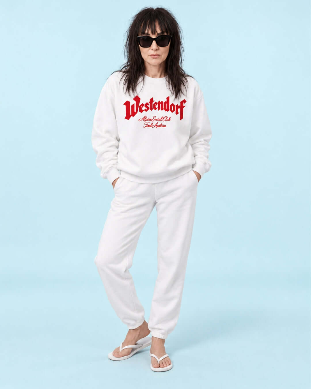 Helga wearing the White Westendorf Alpine Social Club Heavy Sweater with red print and matching white joggers.