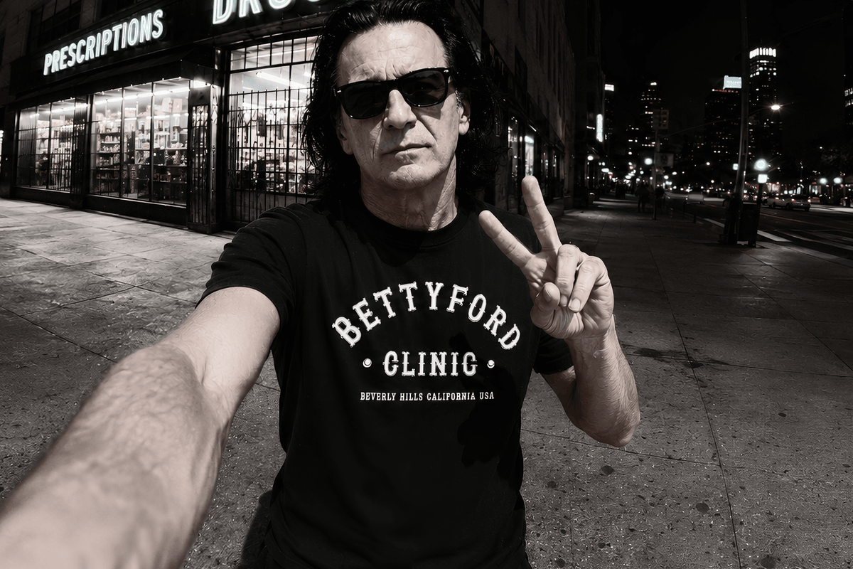 Person in a Betty Ford Clinic t-shirt making a peace sign on a city street, highlighting pop culture influence.
